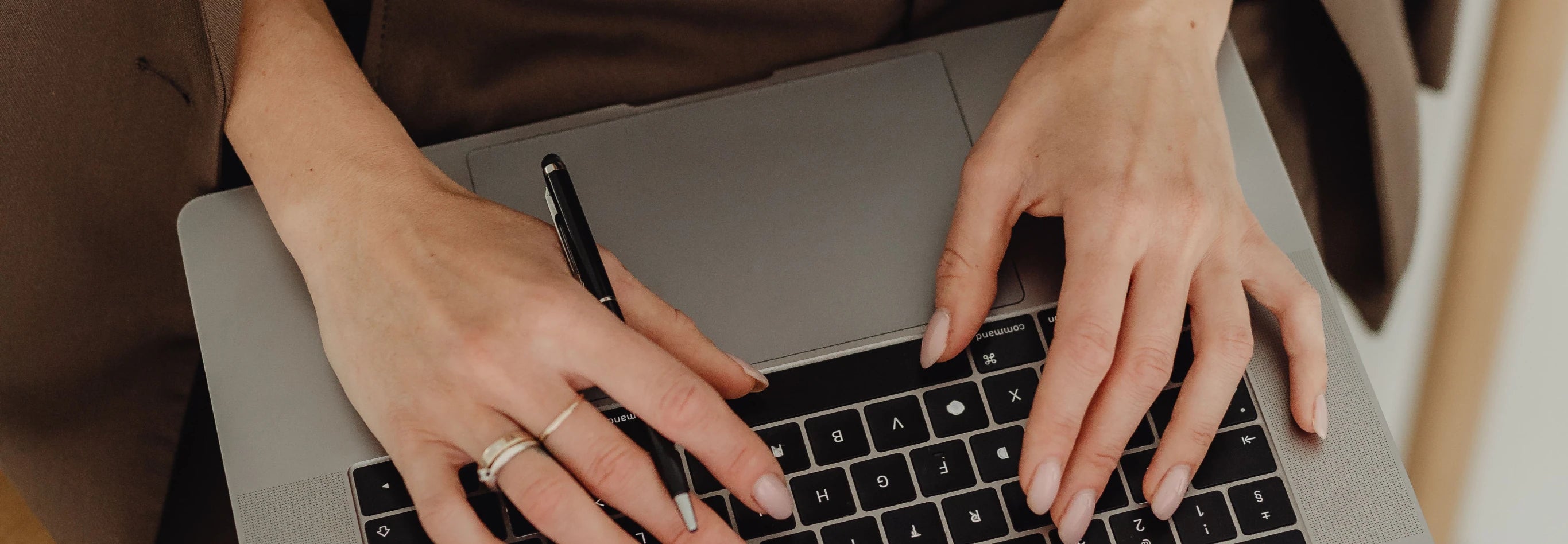 Eine Frau im braunen Anzug, die neben IWC HOME-Stoffmustern an einem Laptop arbeitet