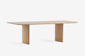 Jasny drewniany stół na białym tle z dwiema szerokimi nogami.